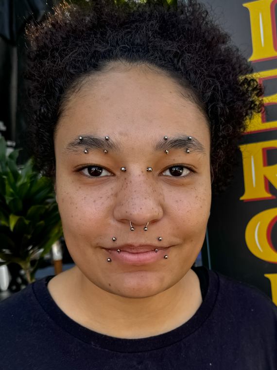 Cliente com piercings faciais