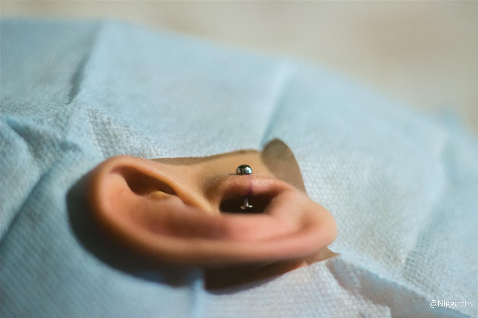 Piercing na orelha com material cirúrgico